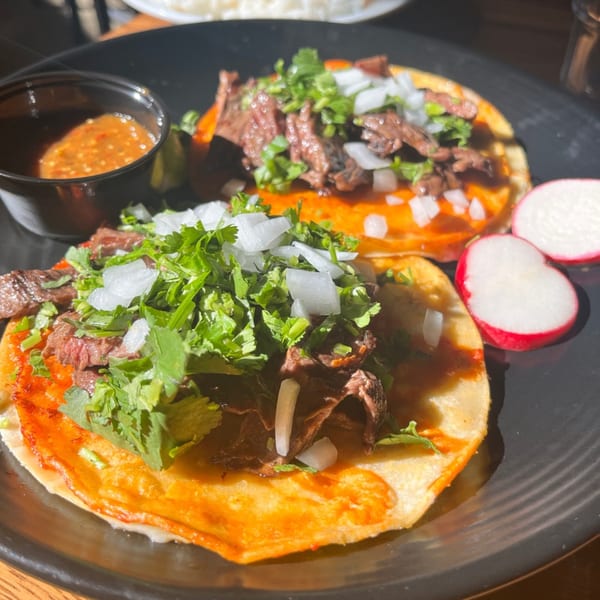 Two Loco Chon Bar & Grill Mexican Restaurant tacos with meat, cilantro, onions, sauce, and radishes.