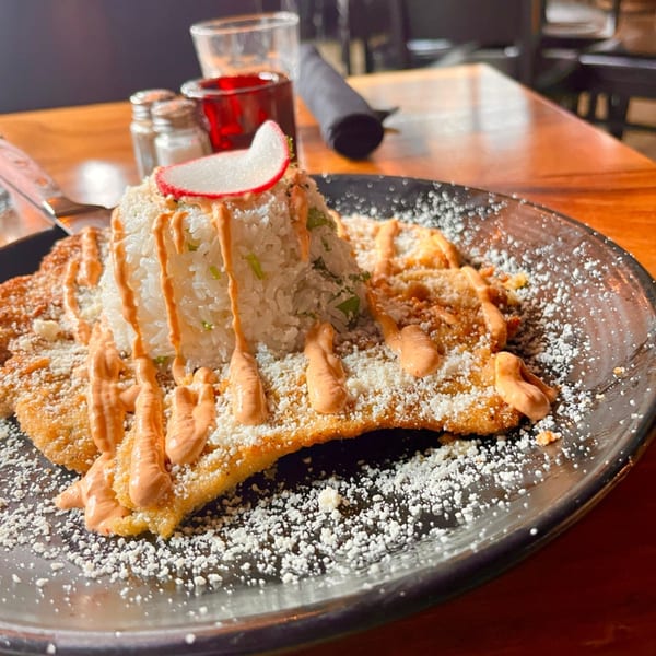 Fried chicken with rice, drizzled with sauce, and topped with a radish slice.